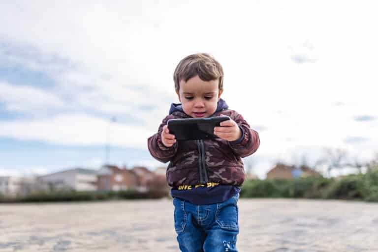 Children surfing the internet outdoors on a iPhone